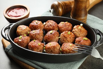 Tasty meatballs in baking dish served on grey table, closeup