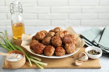 Many delicious meatballs, green onion, garlic, oil and spices on light textured table