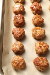 Many delicious meatballs on parchment in baking dish, above view