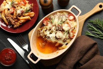 Flat lay composition with delicious pasta casserole on dark textured table