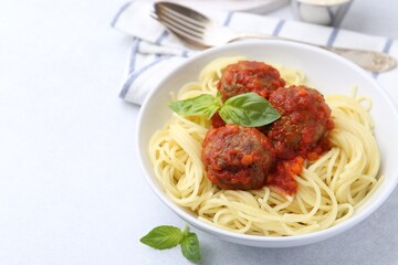 Delicious pasta with meatballs in bowl on light table, closeup. Space for text
