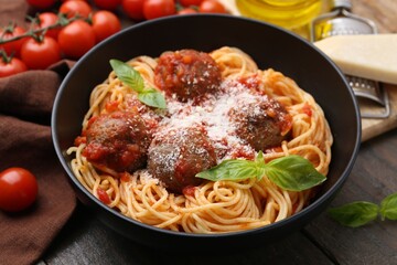 Delicious pasta with meatballs and cheese in bowl on wooden table, closeup