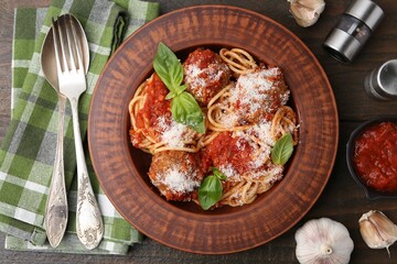 Delicious pasta with meatballs, cheese, spices and tomato sauce on wooden table, flat lay