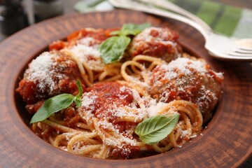Delicious pasta with meatballs, cheese and basil on plate, closeup