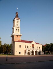 Obraz premium Ancient building of the town hall with a clock tower and a historic chapel on the central square of the city on a sunny day. An architectural ensemble with elements of baroque and classicism, surround