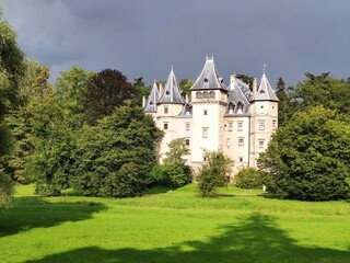 Photo showing the castle in Gołuchów in Poland at sunset, in summer, surrounded by a park.
