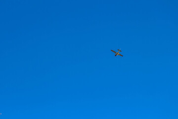 Small airplane flying high in clear blue sky during daylight