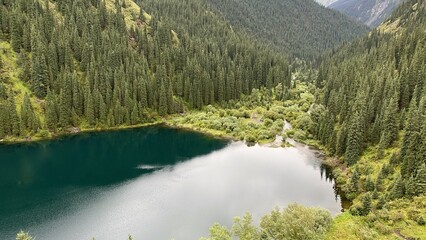 Landscape of mountain lake Kolsay with blue water among evergreen mountains