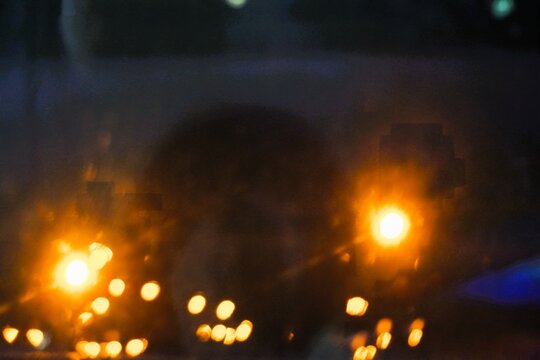 Abstraktes Motiv von parkendem Bus mit goldgelb-orangenen Lichtern bei Eis, Glätte und Kälte in der Nacht im Winter