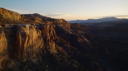 Obraz premium A majestic canyon landscape at sunrise with the warm glow highlighting the rugged rock formations