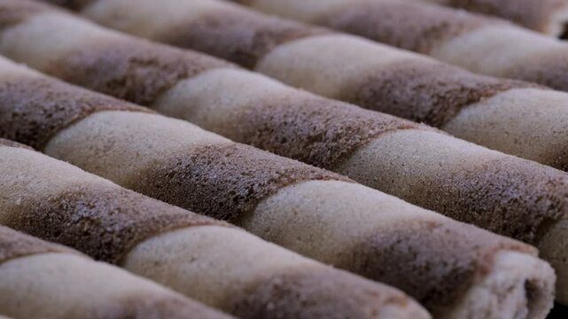 Macro view of cream filled wafer rolls stack together. Slider shot. Depth of field, selective focus. Dessert, snack, sweets or confectionery treats concepts. 4k