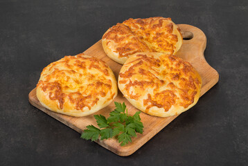 National Georgian khachapuri. Flatbread with cheese. On a wooden board. Dark background. Close up