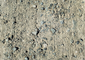 Slag and gravel in the form of small gray stones, seen from above. Old road surface transformed by time and temperature changes into ruins. Dirt road.