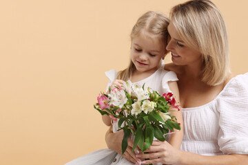 Little daughter congratulating her mom with bouquet of alstroemeria flowers on beige background, space for text. Happy Mother's Day