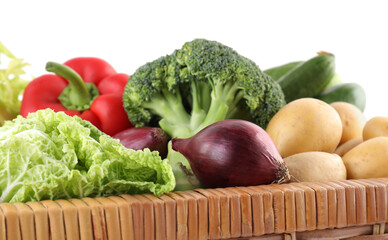Different ripe vegetables in wicker box isolated on white