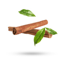 Cinnamon sticks and green leaves in air on white background