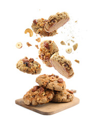 Yummy nut cookies falling onto wooden board on white background