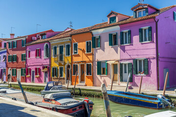 Italy, Burano. Canal and colorful buildings the island is known for. Small boats moored to the...