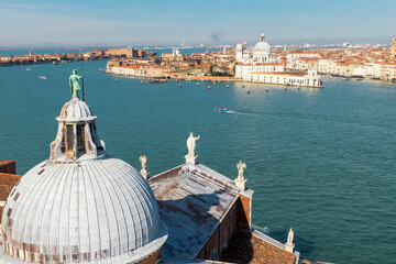 Italy, Venice. Seen from the campanile of San Giorgio Maggiore, the church's dome and roof with statue of a Guardian Angel. In the distance is Church of Santa Maria della Salute.