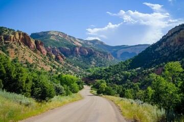 Fototapeta premium Gravel road winds through green valley, colorful cliffs.