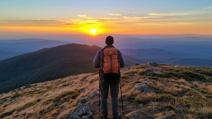 Fototapeta premium A hiker stands on a mountain peak, gazing at a breathtaking sunset over rolling hills and valleys.
