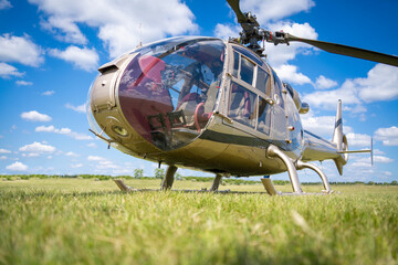 Modern small transport helicopter on a grassy airfield with a cloudy blue sky in the background © ZenitX