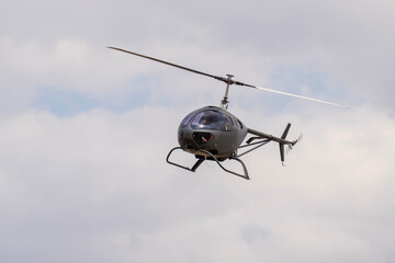 Modern gray two-seater small helicopter flying in the air
