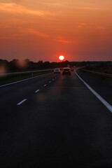 Scenic highway at sunset with cars and trucks driving  through a dirty windshield. Concept of travel, transportation, freedom and the beauty of evening skies on the open road. Copy space