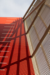 Red building at sunset with grate casting a shadow.