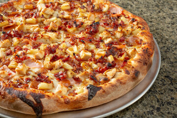 A view of a meaty Hawaiian pizza.