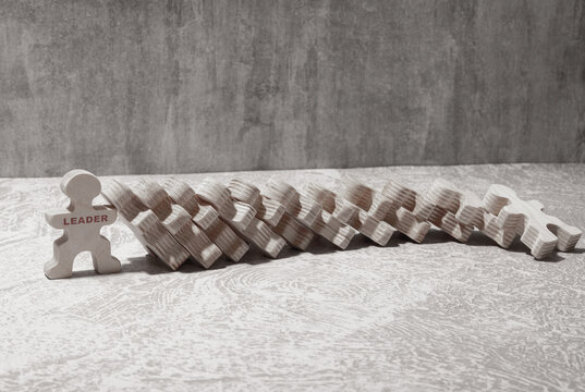 Close-up Of Businesswoman Stopping The Effect Of Domino With Hand At Desk.