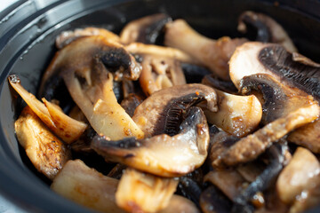 A closeup view of a container of sliced grilled mushrooms.