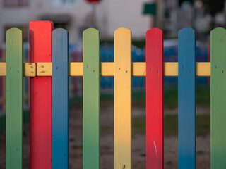 The colorful painted wooden boards on the fence around a playground are illuminated by the rays of the setting sun. Pula, Croatia - January 3, 2025