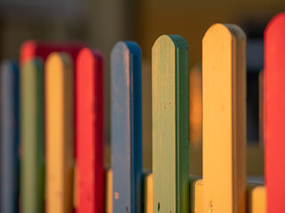 The colorful painted wooden boards on the fence around a playground are illuminated by the rays of the setting sun. Pula, Croatia - January 3, 2025