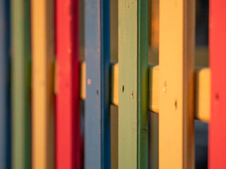 The colorful painted wooden boards on the fence around a playground are illuminated by the rays of the setting sun. Pula, Croatia - January 3, 2025