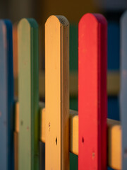 The colorful painted wooden boards on the fence around a playground are illuminated by the rays of the setting sun. Pula, Croatia - January 3, 2025