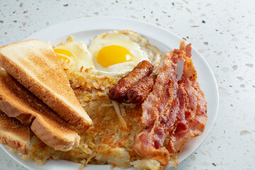 A view of a bacon sausage egg breakfast plate.