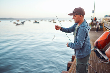 Fisherman putting bait on hook, preparing fishing rod on pier