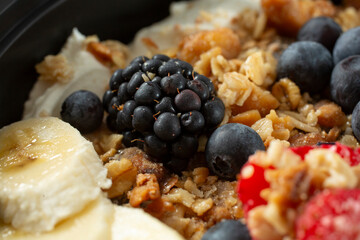 A close up view of fruit and granola toppings in a yogurt bowl.
