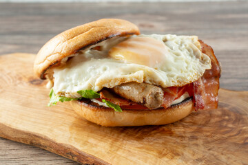 A view of a bagel breakfast sandwich, featuring egg, bacon, sausage.