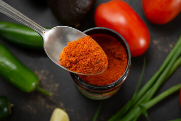 A top down view of a spoon scooping some tomato chicken bouillon from a container.