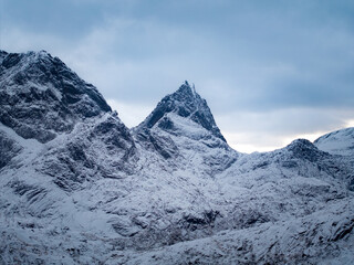 Majestic and breathtaking snowcapped peaks rise elegantly under a cloudy sky backdrop