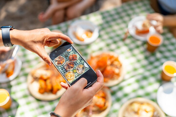 Happy man and woman travel at the sea on summer beach holiday vacation. Asian man using smartphone taking picture of food and drink during having lunch eating seafood with friends on tropical beach.