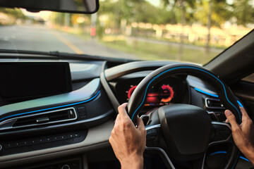 photograph of steering wheel and console of a car riding on the freeway in sunrise  shot with vary shallow focusing that keep most of photograph out of focus blurred