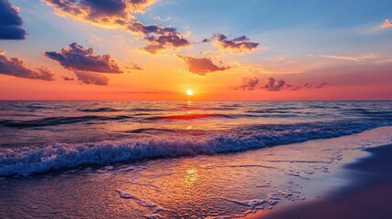Tranquil sunset over the ocean with vibrant colors and gentle waves illuminating the sandy beach in a picturesque coastal scene.