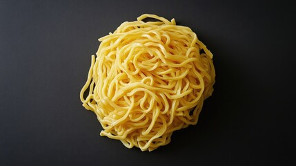 Yellow cooked noodles arranged in a messy pile on a dark surface showcasing texture and color for culinary or food-related concepts.