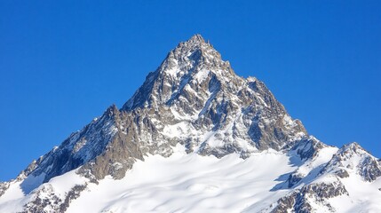 A majestic snow-capped mountain peak against a clear blue sky.