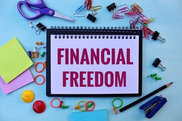 FINANCIAL FREEDOM text on notebook with scissors, calculator and pencil 