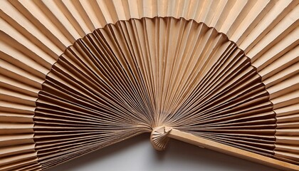 Close-up of a beige hand fan, showcasing intricate pleats and craftsmanship.