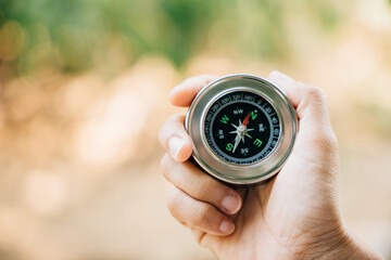 A traveler holding a compass in a park seeks guidance and direction. The compass in a woman hand...